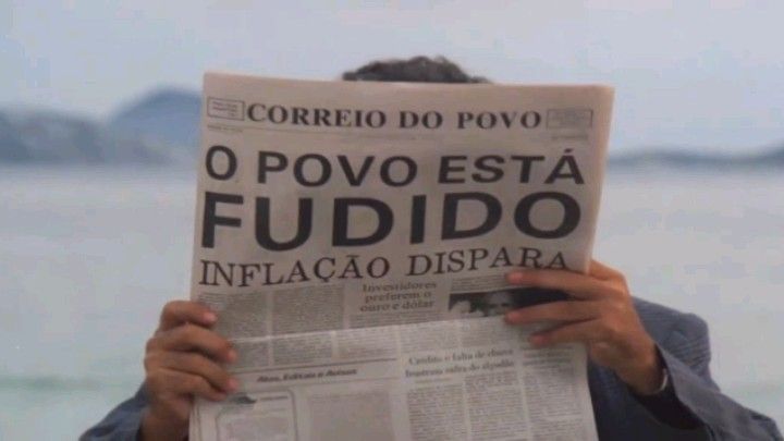 um cara segurando um jornal que diz 'o povo esta fudido! inflação sobe'